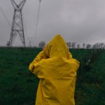 Person in yellow raincoat looking at power line